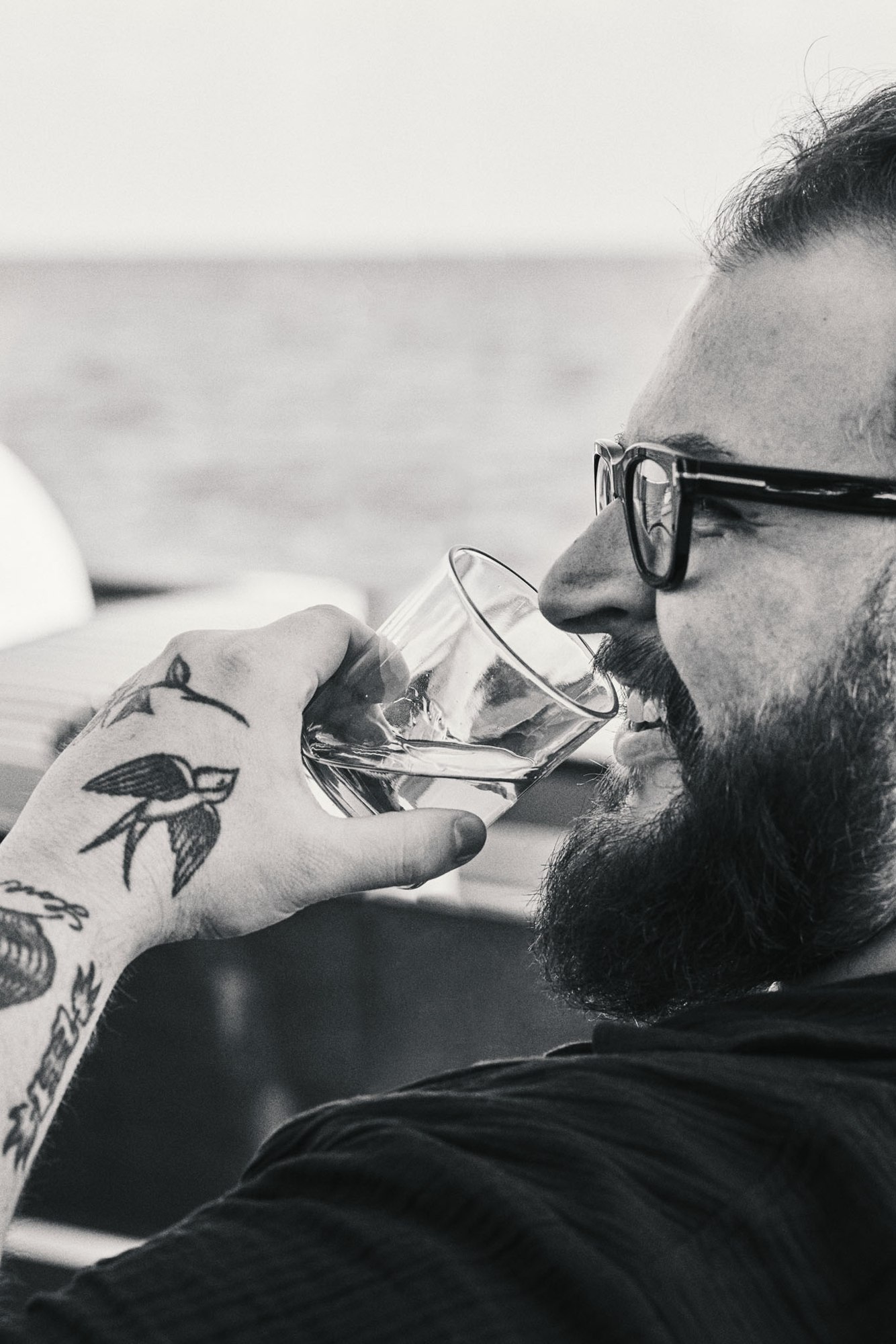 Black-and-white portrait of a man enjoying a glass of whiskey